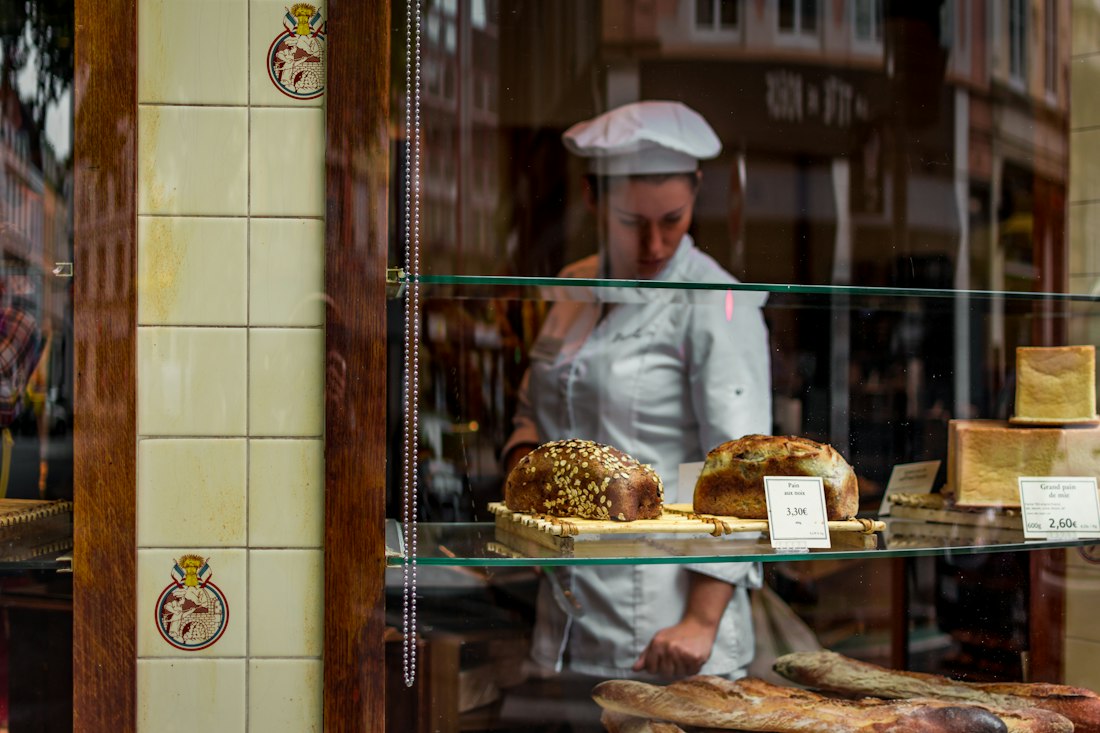 Padeiro atrás da vitrine de uma padaria de bairro