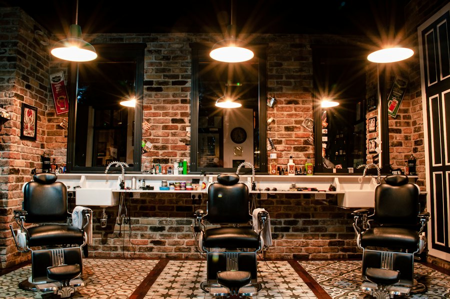 Barbearia com cadeiras de couro e parede de tijolos