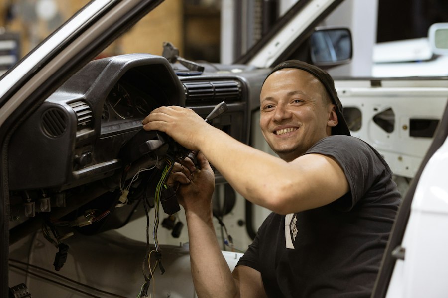 Mecânico sorrindo dentro de um carro, na oficina