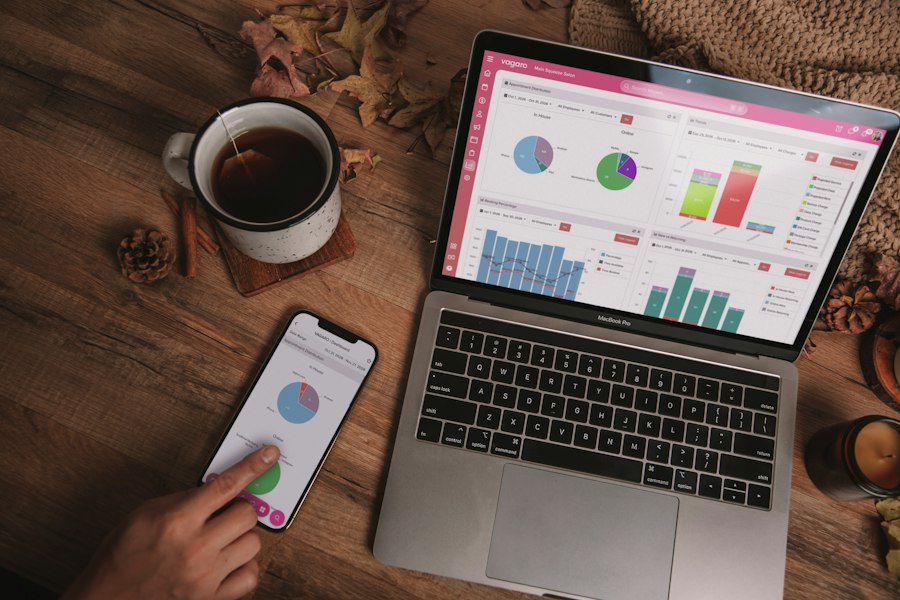 Laptop e celular com painéis de resultados sobre uma mesa de madeira